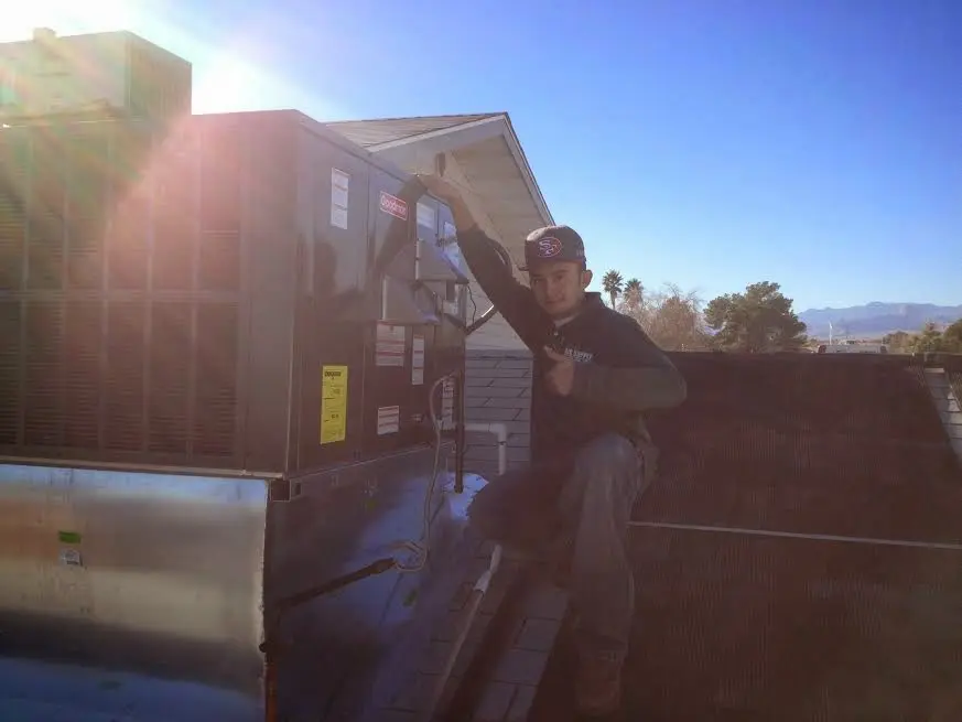 HVAC technician performing AC Tune-Up on a rooftop unit in Wolfeboro